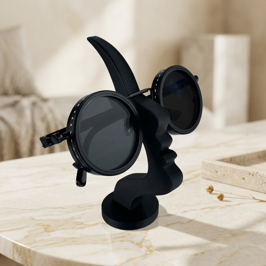 Black face-shaped glasses stand holding round sunglasses on a light-colored tabletop.