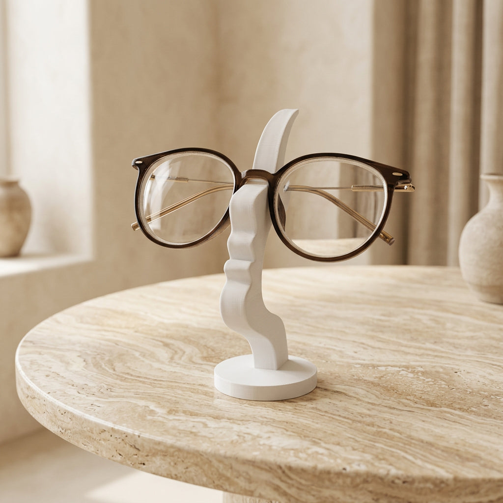 White sculptural eyeglass holder displaying round gold-frame glasses beside a black glasses stand. 